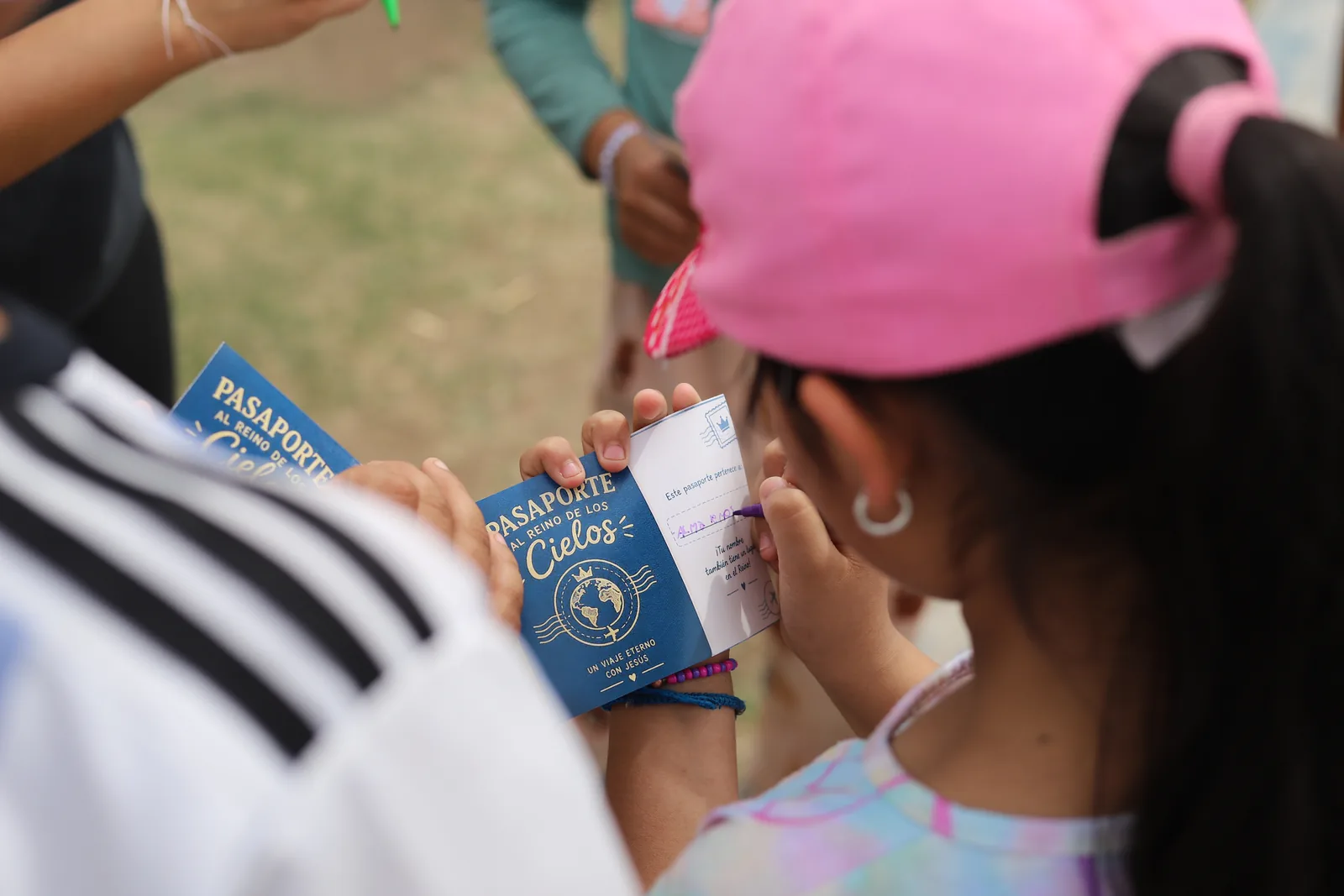 Una nena escribe su nombre en el Pasaporte al Reino de los Cielos, durante una actividad en el barrio.