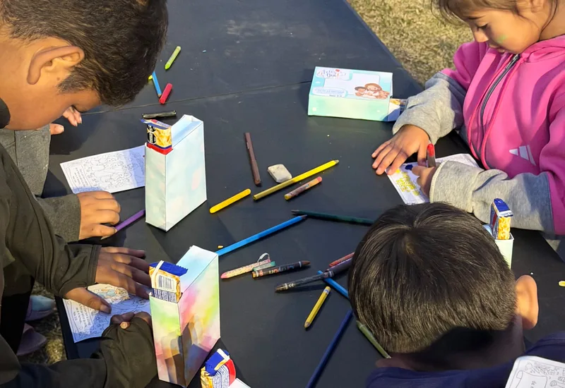 Niños dibujando y armando manualidades sobre una mesa, en la Escuela Bíblica.